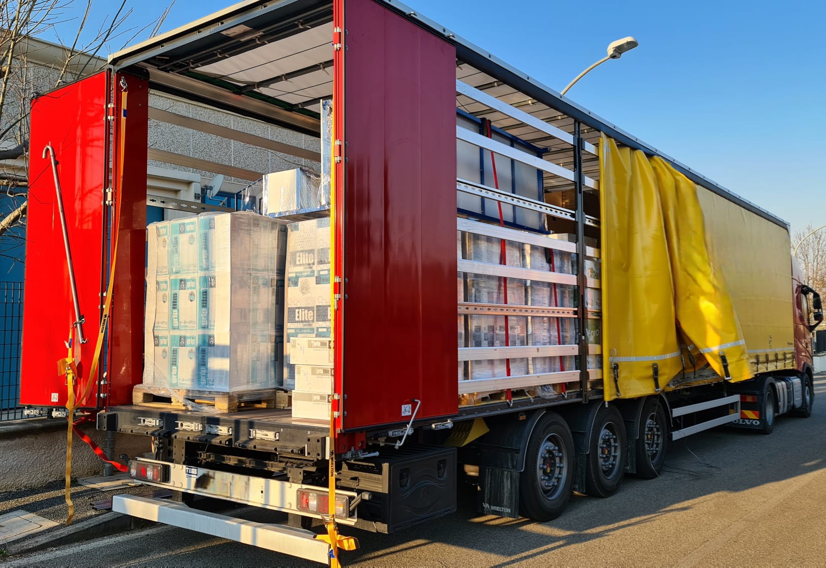 Załadowana naczepa firanka z paletami i pakietami blatów zabezpieczonymi pasami transportowymi
